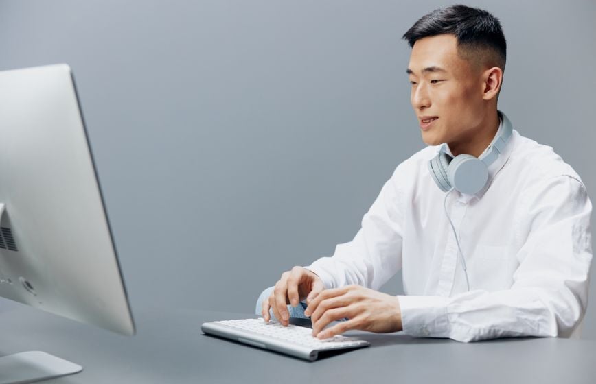 Man working at a computer with headphones around his neck.